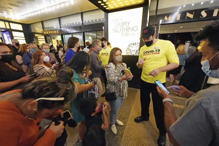 A photo of theatergoers showing proof of vaccination before a performance of "The Lion King,"